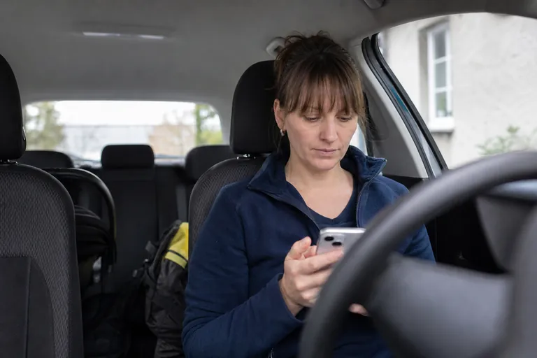 Hebamme prüft im Auto einen digitalen Eintrag zu einem Hausbesuch